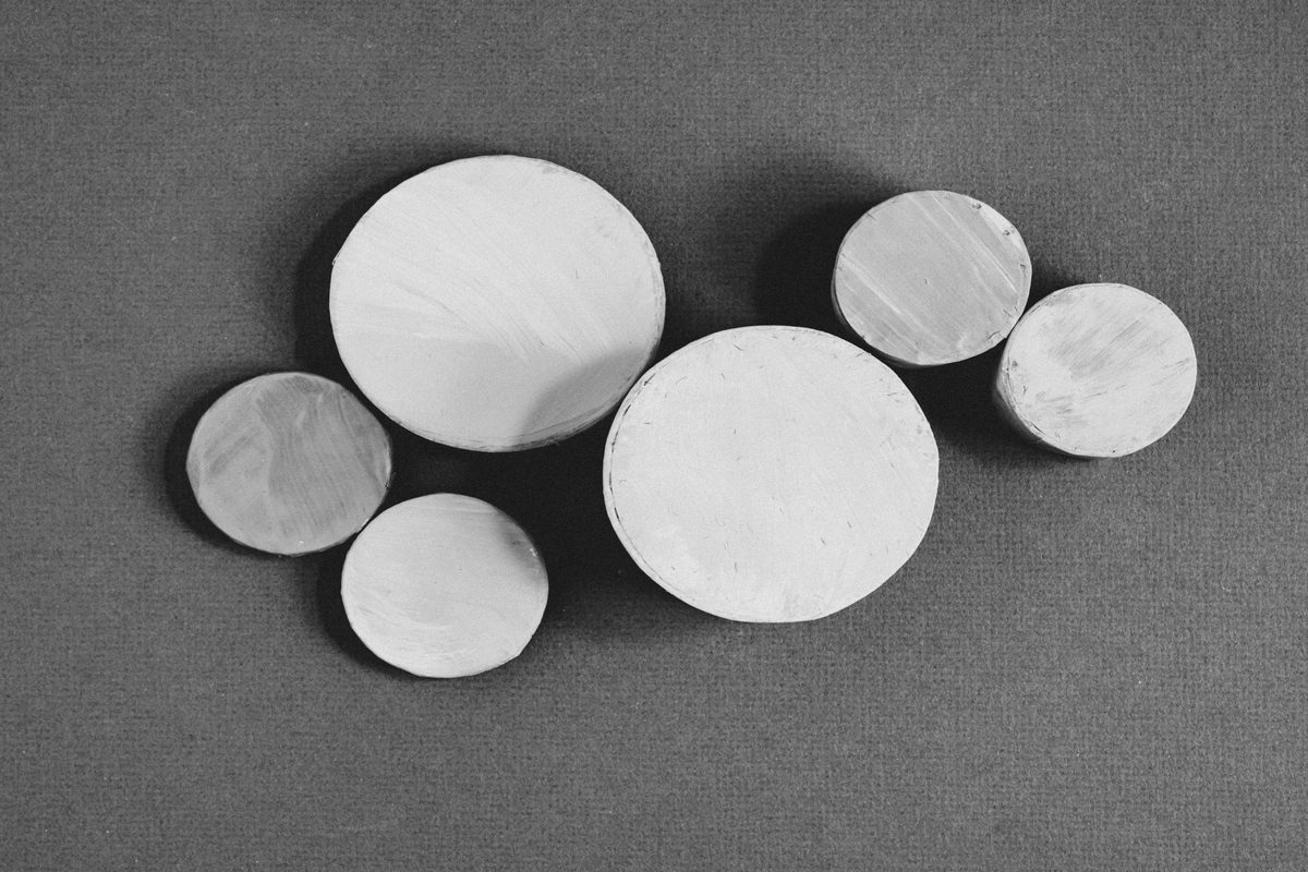Discos de arcilla de tamaño variable vistos desde arriba, varios tocándose entre sí sin traslape: el principio de empaquetado de círculos que organiza un circle packing por tamaño