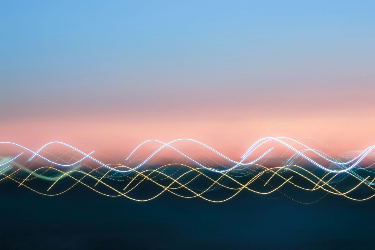 Trazos de luz translúcidos y ondulados que se cruzan y superponen en el aire contra un atardecer, sin línea base fija: la misma anatomía de un stream graph, donde varias bandas fluyen centradas en torno a un eje en vez de apilarse desde cero